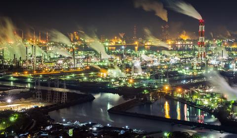 un ouvrier avec son ordinateur face à une usine