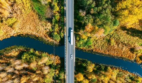 Logistics trucks crossing a tropical river bridge.