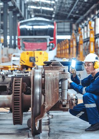 Railway engineer performing electric train inspections at a maintenance station