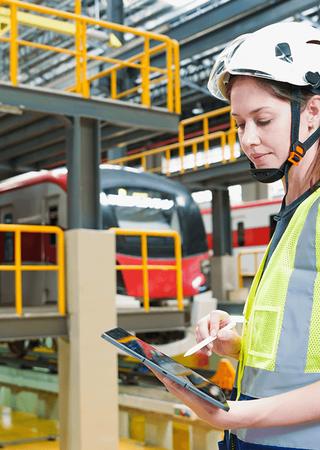 Railway technician working with a laptop and tablet in a rail maintenance plant